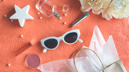 Sunglasses and make up products on the peach color backgroundの写真素材