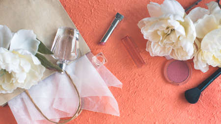 Paper bag, make up and perfume on the peach color backgroundの写真素材