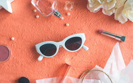 Sunglasses, lipstick and perfume on the peach color backgroundの写真素材