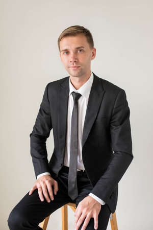 Portrait of a handsome sitting business man, isolated on grey backgroundの写真素材