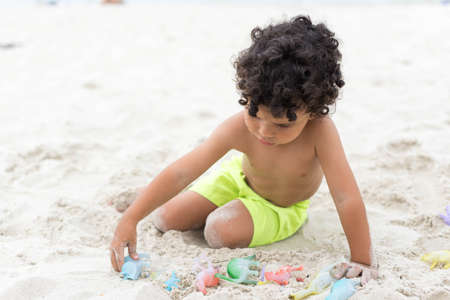 Boy playing with sand on the beach. Holidayの写真素材
