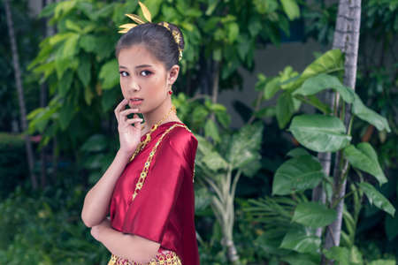 Young asian girl wearing thai traditional dress and holding flowers. Horizontalの写真素材