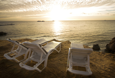 Three sun loungers on the beach with sunset in the backgroundの写真素材