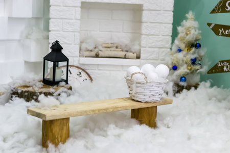 Winter New Year interior. Fireplace. lantern, bench, snow balls, Christmas tree with balls. Cozy decor in white tones in the interior of the Christmas room, a Christmas tree decorated with garlands, gifts. A festive living room in the house. New Years holidays. High quality photoの写真素材