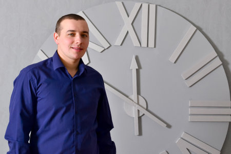 Man smiling against white clock. Young man smiling, positive, relaxed, satisfied attitude, against white clock. Business concept. Free space. High quality photoの写真素材