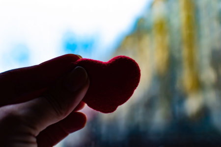 Red heart in womans hand on grey background. The concept of charity, love, donate and helping hand. International cardiology day. A woman gives a red heart to the mans handsの写真素材
