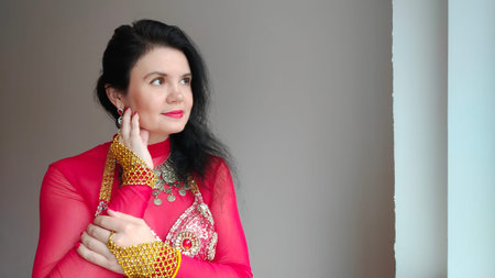 A dancer in a red suit is performing an oriental dance on a white background. Free space for text....