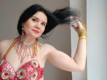 A dancer in a red suit is dancing an oriental dance on a white background. Free space for text....