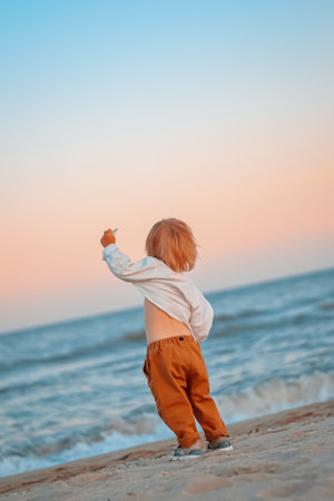 Happy child child wearing a white shirt next to the sea going next to the sea. Place for text. Copy space. Happy child going in the beach Kid having fun outdoors. Summer vacation and healthy lifestyle concept.の写真素材