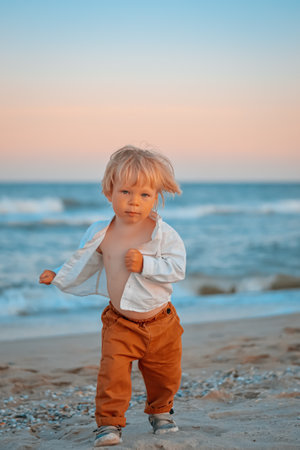 Happy child child wearing a white shirt next to the sea going next to the sea. Place for text. Copy space. Happy child going in the beach Kid having fun outdoors. Summer vacation and healthy lifestyle concept.の写真素材