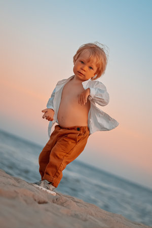 Happy child child wearing a white shirt next to the sea going next to the sea. Place for text. Copy space. Happy child going in the beach Kid having fun outdoors. Summer vacation and healthy lifestyle concept.の写真素材