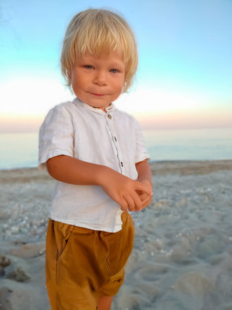 Happy child child wearing a white shirt next to the sea going next to the sea. Place for text. Copy space. Happy child going in the beach Kid having fun outdoors. Summer vacation and healthy lifestyle concept.の写真素材