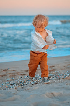 Happy child child wearing a white shirt next to the sea going next to the sea. Place for text. Copy space. Happy child going in the beach Kid having fun outdoors. Summer vacation and healthy lifestyle concept.の写真素材