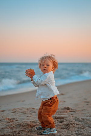 Happy child child wearing a white shirt next to the sea going next to the sea. Place for text. Copy space. Happy child going in the beach Kid having fun outdoors. Summer vacation and healthy lifestyle concept.の写真素材