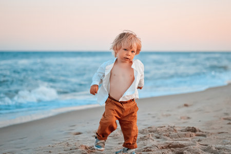 Happy child child wearing a white shirt next to the sea going next to the sea. Place for text. Copy space. Happy child going in the beach Kid having fun outdoors. Summer vacation and healthy lifestyle concept.の写真素材