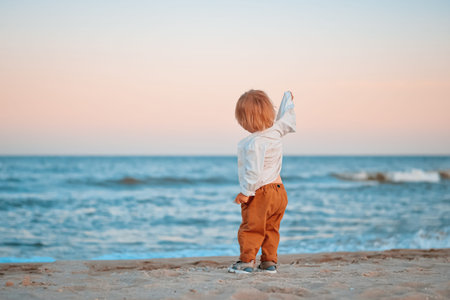 Happy child child wearing a white shirt next to the sea going next to the sea. Place for text. Copy space. Happy child going in the beach Kid having fun outdoors. Summer vacation and healthy lifestyle concept.の写真素材