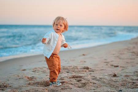 Happy child child wearing a white shirt next to the sea going next to the sea. Place for text. Copy space. Happy child going in the beach Kid having fun outdoors. Summer vacation and healthy lifestyle concept.の写真素材