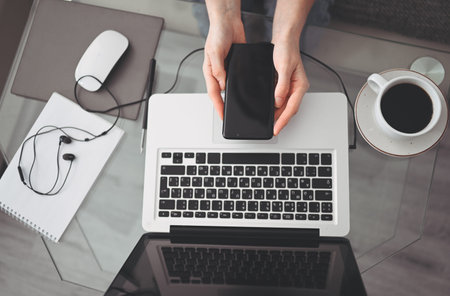 Female hands using smart phone in interior workplace, freelance business woman using cell phone at...