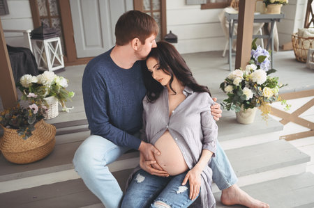 Pregnancy and people concept - happy man hugging his beautiful pregnant wife at home. Future parents waiting unborn baby. Love, relationship, birth, happy family concept - young lovely married coupleの写真素材
