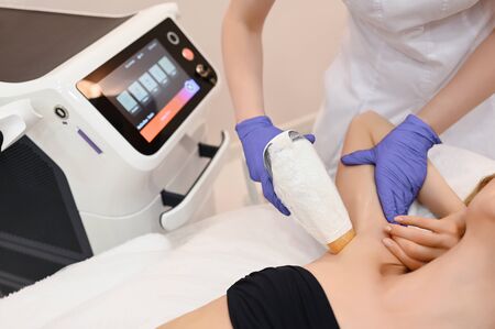 Laser epilation and cosmetology in beauty salon. Hair removal procedure. Laser epilation, cosmetology, spa, and hair removal concept. Beautiful blonde woman getting hair removing on underarmsの写真素材