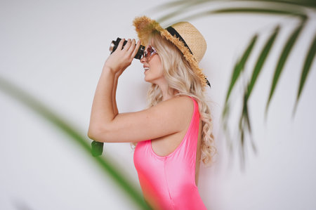 Young smiling happy blonde in a pink swimsuit, a straw hat, sunglasses, excited to present product....