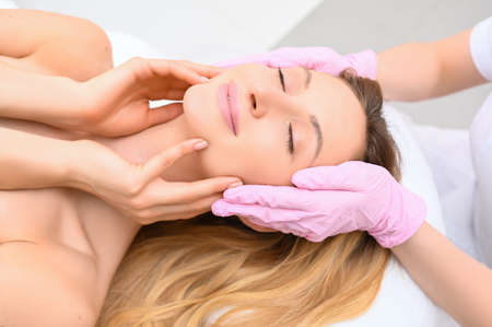 Closeup of beautician hands in gloves touching young womans face. Plastic surgery concept. Facial beauty.の写真素材