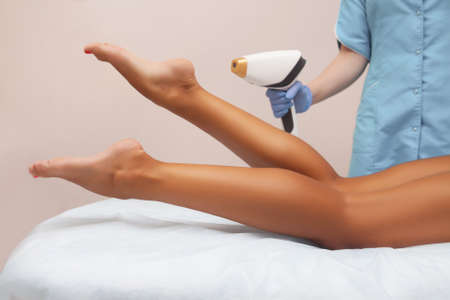 Laser epilation and cosmetology in beauty salon. Hair removal procedure. Laser epilation, cosmetology, spa, and hair removal concept. Beautiful woman getting hair removing on legsの写真素材