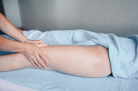 Young unrecognizable woman lying on massage table and enjoying therapeutic massage. Body care,...