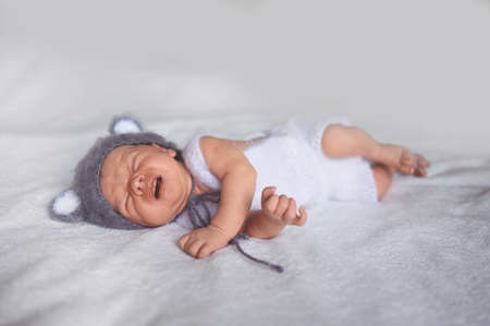 Cute crying newborn little baby boy sleeping in crib in a knitted suit with ears. Baby goods packaging template. Healthy child, concept of hospital and happy motherhood. Infant baby. Nursery.の写真素材