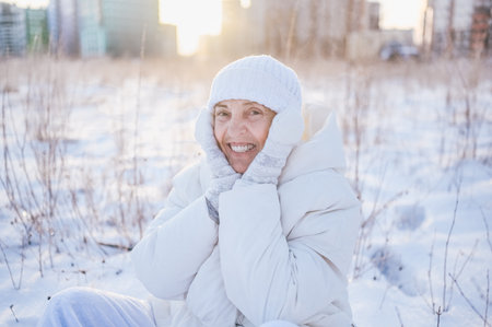 Happy elderly senior mature woman in white warm outwear playing with snow in sunny winter outdoors. Retired healthy people holiday vacation winter activities, active lifestyle conceptの写真素材