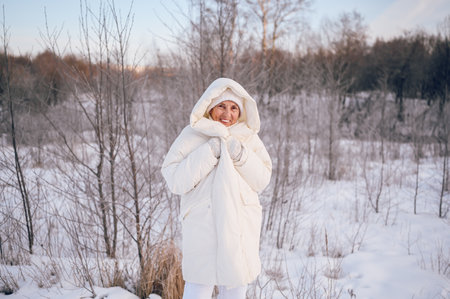 Happy elderly senior mature woman in white warm outwear playing with snow in sunny winter outdoors. Retired healthy people holiday vacation winter activities, active lifestyle conceptの写真素材