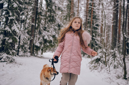 Happy family weekend - little cute girl in pink warm outwear walking having fun with red shiba inu...