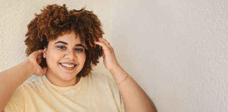 Beautiful happy smiling curvy plus size African black woman afro hair with make up posing in beige t-shirt on white background. Body imperfection, body acceptance, body positive and diversity concept.の写真素材