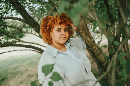 Fashion portrait of young naturally beautiful plus size African American woman in light trouser suit...