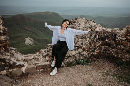 Happy woman tourist hiking up mountain enjoying nature. Landscape in cloudy gloomy windy weather....