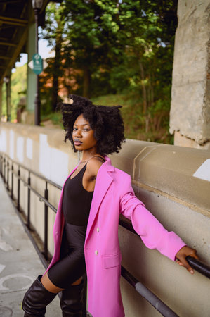 Fashion outdoor street style portrait of Beautiful young African American woman posing outside on urban city landscape summer day wearing pink jacket. Attractive black female, diversity conceptの写真素材