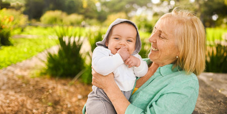 Beautiful happy smiling senior elderly woman holding on hands cute little baby boy. Grandmother and...