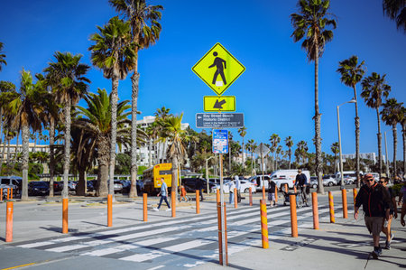 10 March 2024, Los Angeles, USA. Venice beach on a bright sunny day. Crowds of people tourists walking path along pedestrian zone of broadwalk. Cyclists ride on bicycle roadway. Beautiful oceanfrontのeditorial素材