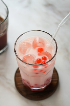 Close up of home made milk bubble tea with tapioca pearls. Strawberry milk tea drink with tapioca balls. Iced milky drink with tapioka bubbles and ice. Bubble tea or boba tea, home interiorの写真素材