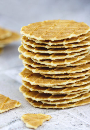Close-up of a stack of butter waffle cookies on a gray background, selective focus vertical image. Waffle crisps close-up. Tasty home made thin wafflesの写真素材