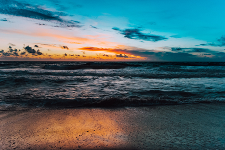 blue sky and orange sunlight reflecting off the ocean at dawnの写真素材