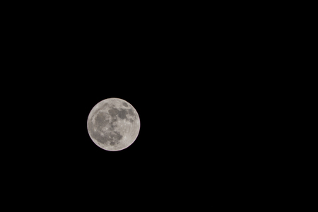 nearly full waxing gibbous moon with dark sky in the backgroundの写真素材