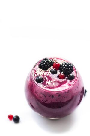 Image of homemade antioxidant berry smoothie with seeds, coconut, cherries and rasberry. Delicious dessert on violet background with fruitsの写真素材