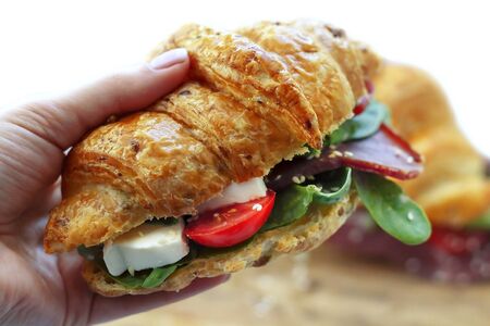 Breakfast croissants sandwich with meat, cheese, tomatos, avocado and green spinah isolated on white backgroundの写真素材