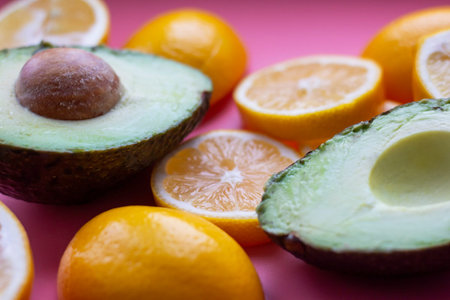 Flat lay composition with yellow lemons and green avocado, and space for text on color pink...