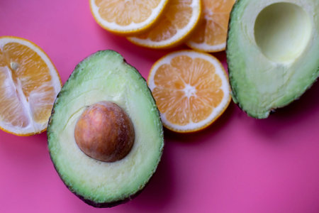 Flat lay composition with yellow lemons and green avocado, and space for text on color pink...