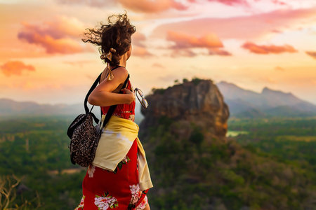 Beautiful curly girl standing on the Pidurangala Rock. Sigiriya, Sri Lanka and watching beautiful pink sunset.の写真素材