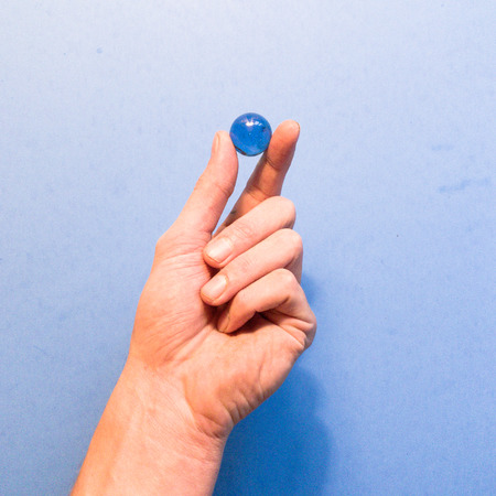 Hand holding a blue marbleの写真素材