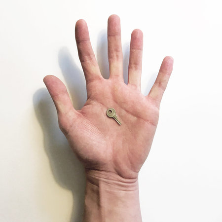 Hand holding a tiny keyの写真素材