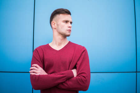 young guy in a red sweater on a blue backgroundの写真素材